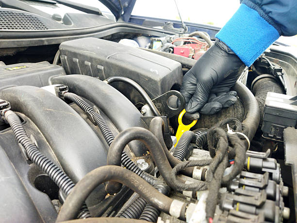 istock Car engine inspection with mechanic's hand on dipstick 2244444701