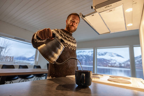 Man Pouring Hot Drink in Cozy Kitchen with View