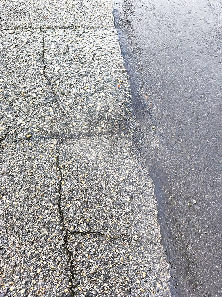 istock Wet asphalt and cracked pavement texture after a rain shower 2244449525