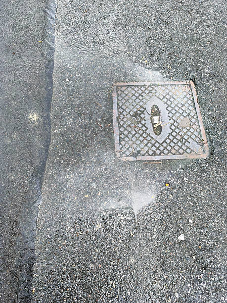 istock Water flowing from a manhole cover on a wet asphalt surface 2244449782