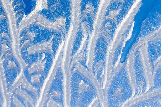 Iced windows in winter. Frost creates all kind of figures on window. Blue sky