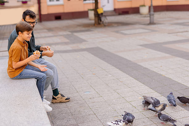 Parent and Child Having Fun Enjoying Outdoors While Feeding Pigeons