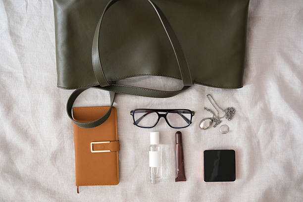 istock A stylish and chic green bag that is filled with all the essential items you need for work and daily activities of woman - glasses, copybook, handcream, perfume,lipstick 2244464499