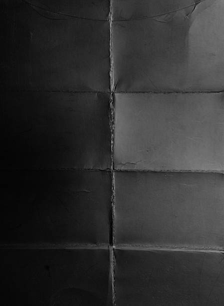 istock High-resolution texture of gray paper or cardboard featuring a clear cross-fold pattern with natural creases and light scratches. 2244465522