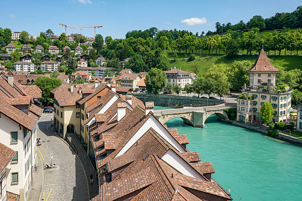 A city Bern in Switzerland with a river running through it and a bridge over it. The buildings are old and have a lot of character