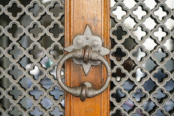 An antique wrought iron door handle with decorative patterns, located on a door in Bern, Switzerland. The door is made of metal patterns.