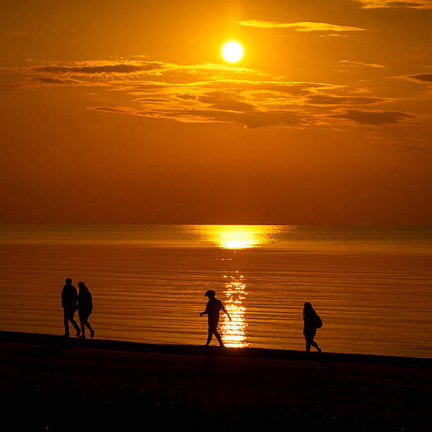 istock A beautiful summer sunset scenery with people silhouettes walking on a beach, enjoying Baltic Sea costline. 2244470251