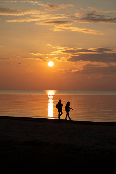 istock A beautiful summer sunset scenery with people silhouettes walking on a beach, enjoying Baltic Sea costline. 2244470287