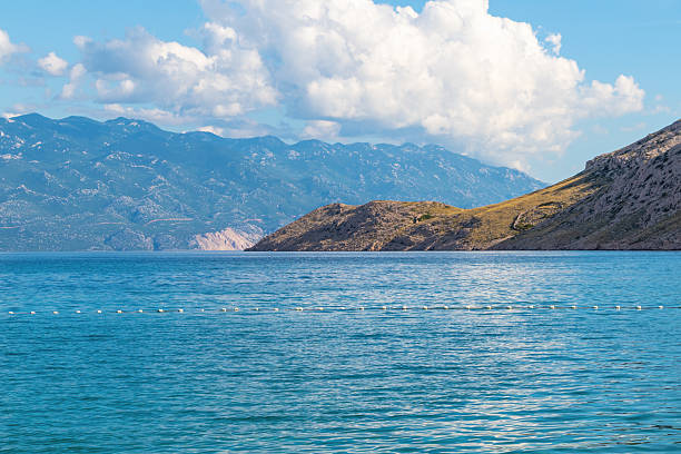 Tranquil seascape with mountain views under cloudy sky. Vela Luka beach, Krk island, Croatia.
