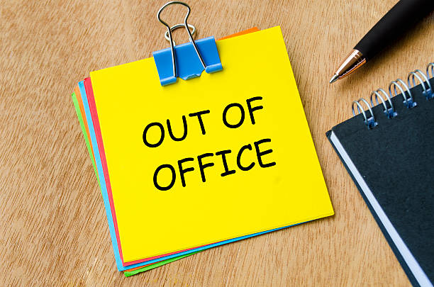 istock Out of office text on yellow notepad with pen and an notebook background. Getaway or on a vacation concept. 2244471765