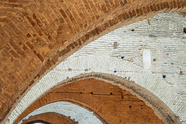 The intricately layered brick arches of the Atarazanas in Seville showcase Gothic design and depth, creating a stunning visual effect at sunset.