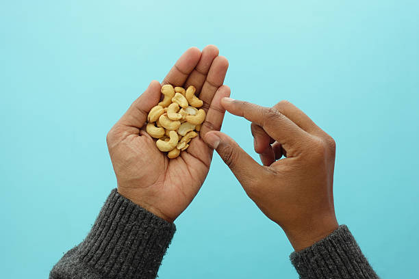 istock Hands holding cashew nuts on a blue background 2244478873