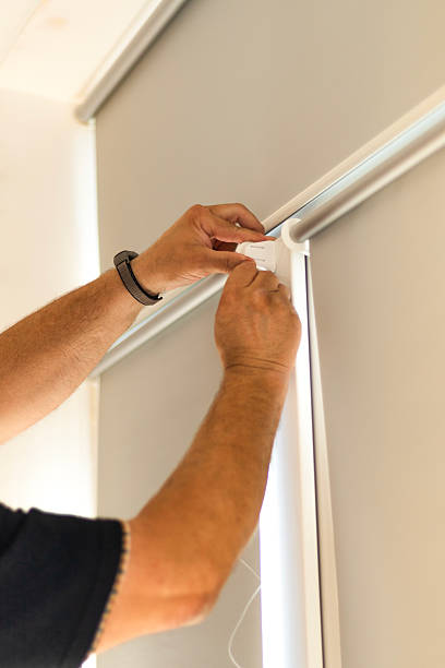 istock Installation of light gray roller blinds with reflective foil coating on windows. 2244479496