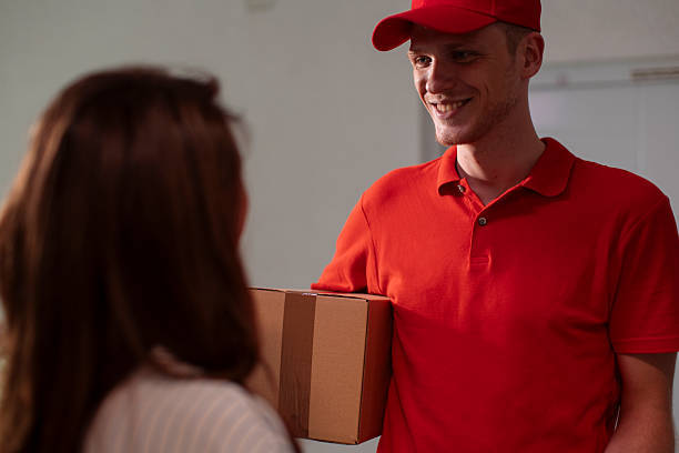 istock Delivery Person in Red Uniform Hands Package to Customer in Friendly Exchange 2244479895