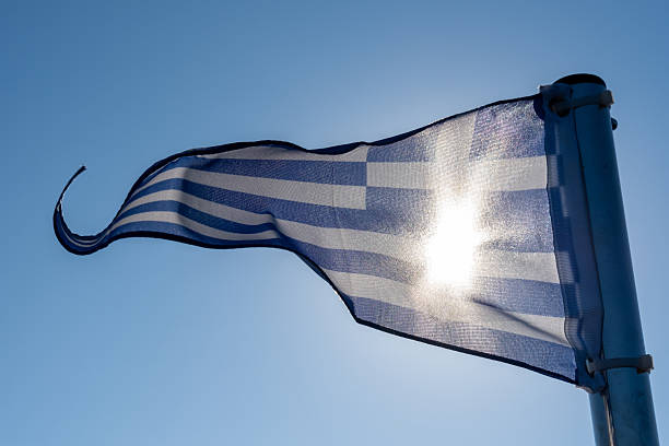 The triangular Greek flag against a blue sky on a sunny day