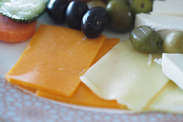 Different kind of cheese served on wooden plate on top of table outdoors
