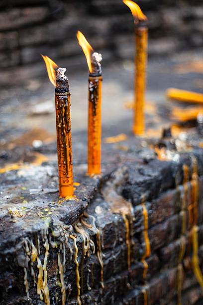 Candles burning as a religious offering with candle wax on a brick wall on an ancient temple in Chiang Rai, Thailand