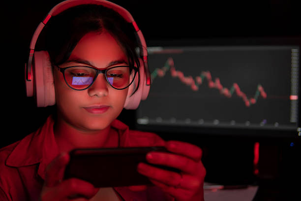 istock Gen Z young woman scrolling through investment trading data and analysing trading graph smartphone. 2244493220
