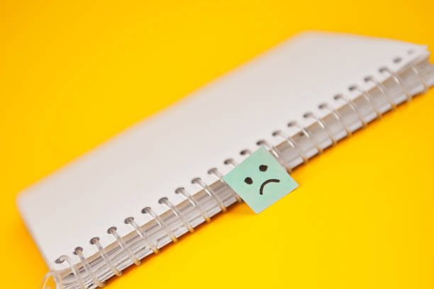 istock Notebook with a sad face tab as a marker, pointing to an issue that needs attention, follow up and corrective action. 2244493448