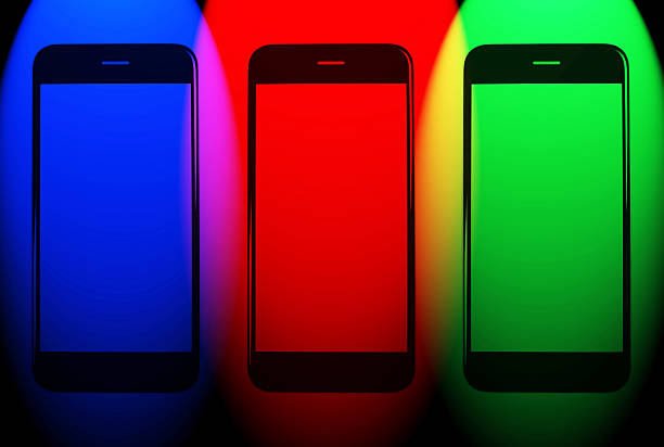 Three smartphones with glowing RGB screens in blue, red, and green light, representing digital display colors, modern technology, and communication concept.