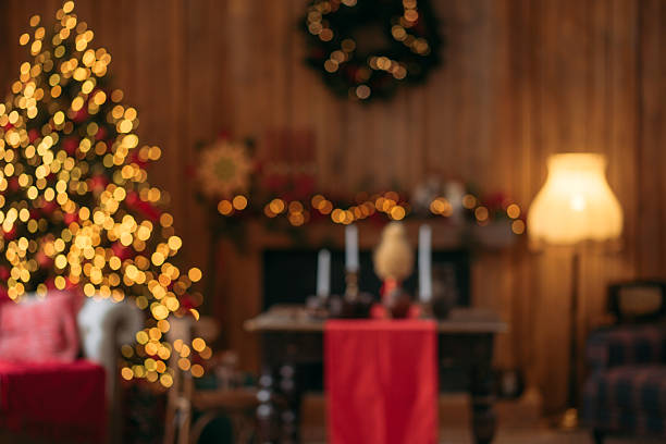 istock A blurred, warm, and cozy interior scene featuring a glowing Christmas tree, holiday decorations, and a lit lamp in a rustic room. 2244507998
