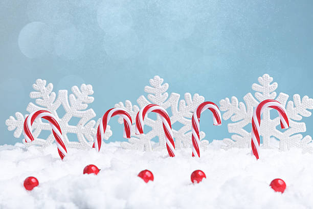 Playful seasonal decoration highlighting red accented peppermint striped candy canes in snow setting