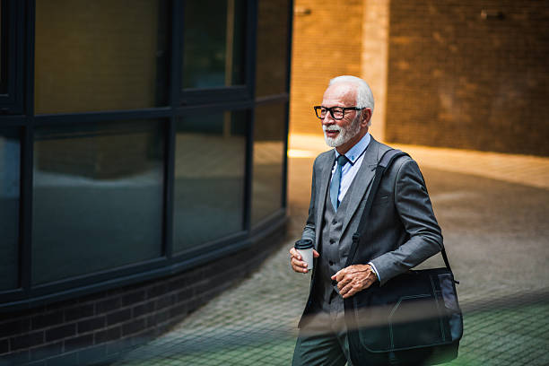 istock Older business man leaving office building with bag and coffee 2244514020