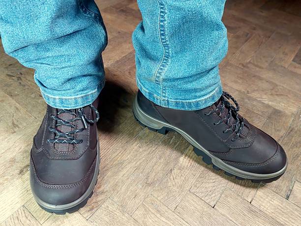 istock Stylish Black Boots Complementing Denim Jeans on a Wooden Floor 2244521378