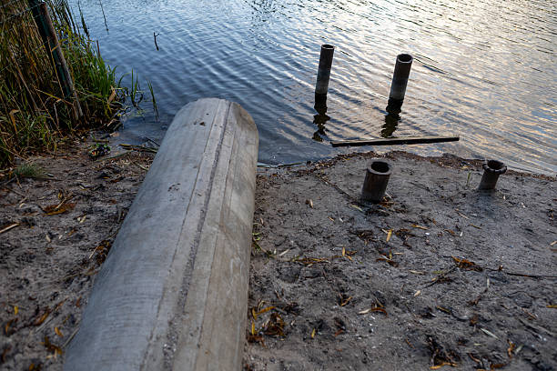 istock Concrete drainage pipe releasing water into a river surrounded by vegetation 2244524199