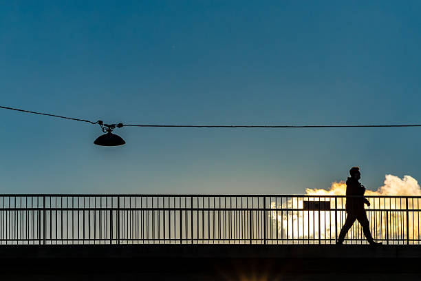 Stockholm, Sweden Oct 1, 2025 A pedestrian walks over a pedestrian bridge in the setting sun.