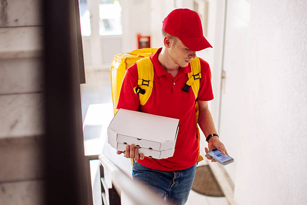 istock Delivery Courier In Red Uniform With Yellow Backpack Holding Pizza Box And Phone 2244540908