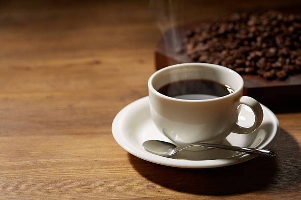 istock Cup of coffee with grains on wooden background 2244547874
