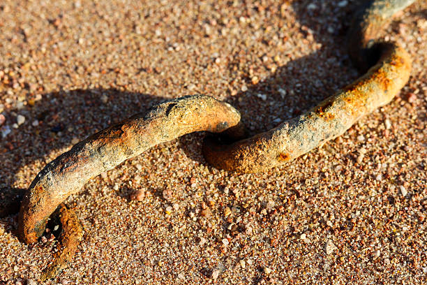 An old rusty iron chain buried in the sand on the beach.