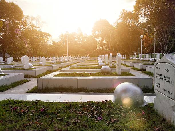 Balikpapan-indonesia 10/09/2024 ​A solemn military cemetery (Taman Makam Pahlawan) bathed in warm, dramatic sunset light, showing rows of white headstones and soldier's helmets in quiet remembrance.