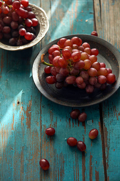 Fresh red grapes are arranged on a rustic wooden table, showcasing their vibrant color and juicy appearance.