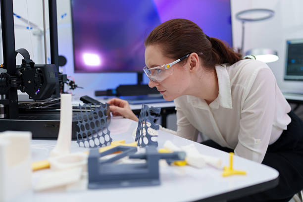 istock Engineers work with a 3D printer to print a clear white plastic model. State-of-the-art technology, selective focus, in a lab. 2244561602
