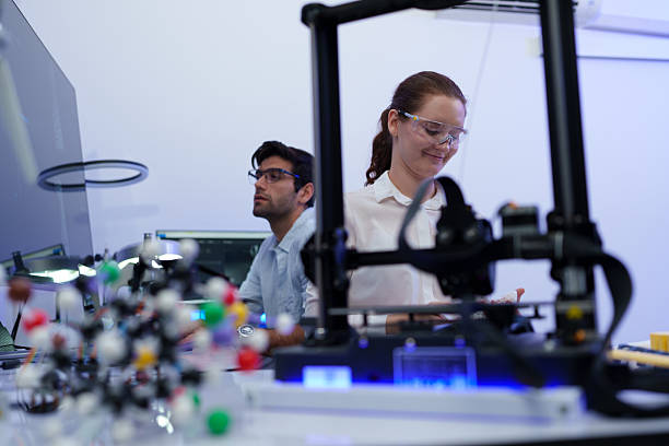 istock Engineers work with a 3D printer to print a clear white plastic model. State-of-the-art technology, selective focus, in a lab. 2244561611