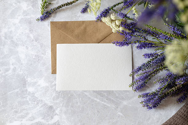 istock Beautiful floral arrangement with blank stationery and an envelope on a marble surface 2244562930
