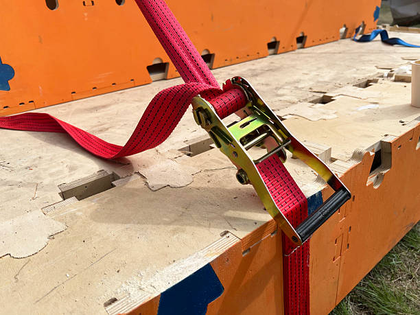 istock Cargo strap secured on wooden platform with bright orange background at outdoor site 2244562974