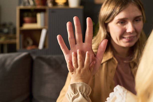 istock Woman Smiling While Touching Hand with Young Child 2244563640