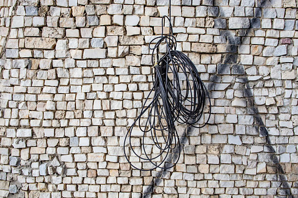 Tangled black electrical wire hanging on stone mosaic  decoration