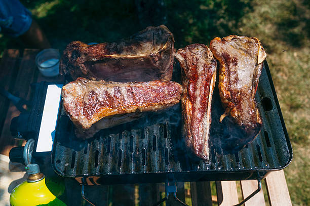 Grilled beef steaks cooking on outdoor barbecue grill.