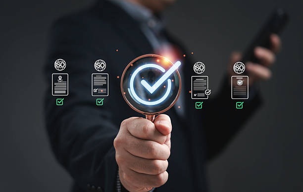 istock Quality and approve concept showing a businessman holding magnifying glass with glowing check mark representing certification standard control assurance validation and business reliability in modern industry 2244570002