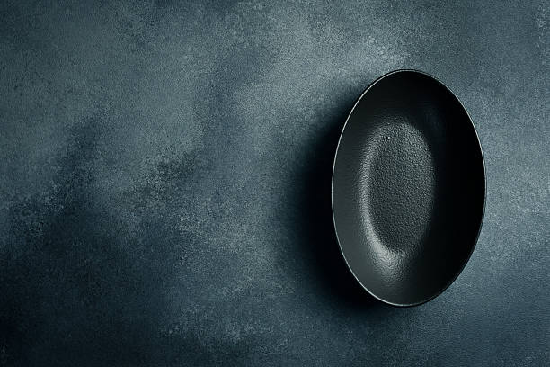 istock Ceramic oval black plate. Close up on gray concrete background. Free space for text. 2244570828