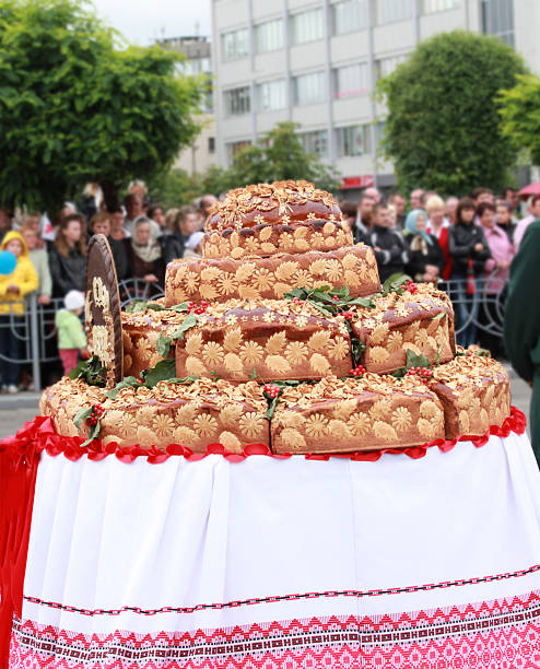 Festive Ukrainian ceremonial bread decorated with dough ornaments and viburnum branches on embroidered cloth during a folk celebration