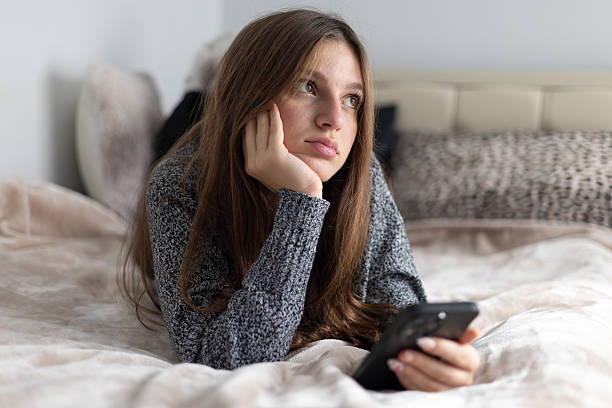 istock Young woman feeling bored and lonely while using a smart phone in bed 2244574567