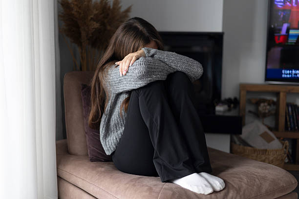 istock Young woman feeling sad and anxious, sitting alone on a couch at home 2244574985