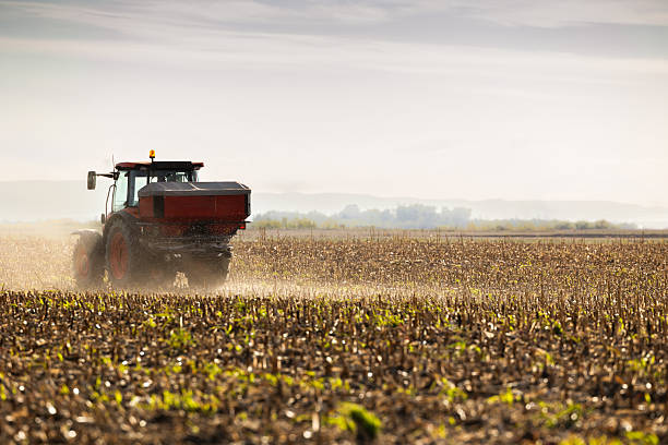 istock Tractor spreading artificial fertilizers in field 2244575927