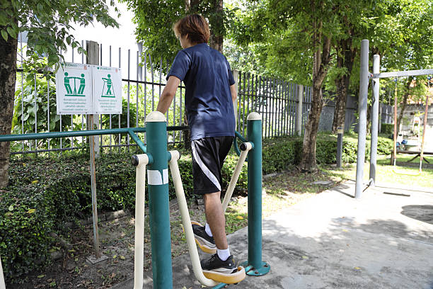 A Southeast Asian man is exercising on an outdoor air walker.