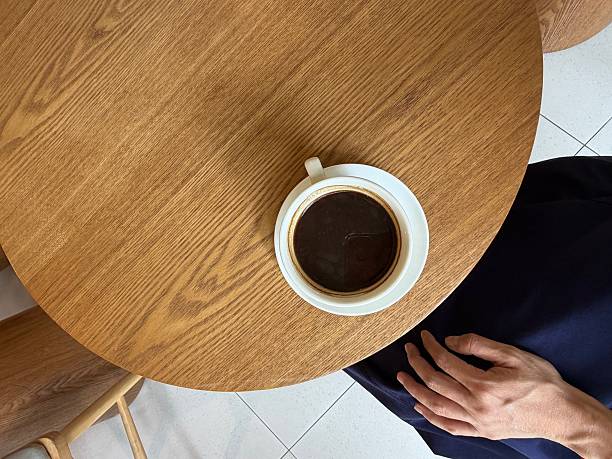 A woman resting at cafe with a cup of coffee on a wooden table — top view, copy space